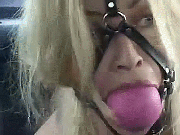 Blonde woman gagged with huge ball gag harness