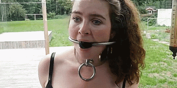 Helpless bondage girl gagged and collared outdoors
