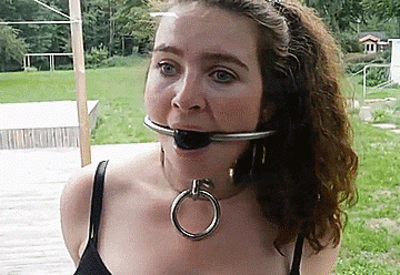 Helpless bondage girl gagged and collared outdoors