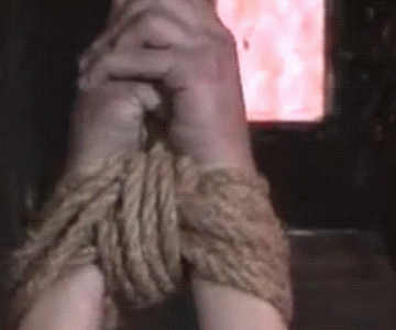 A BDSM Gif showing a strung up woman ball gagged and crying. He rmake-up is running down her face
